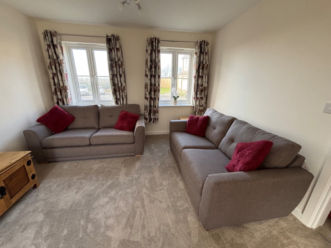 Bright lounge with two grey sofas and red cushions